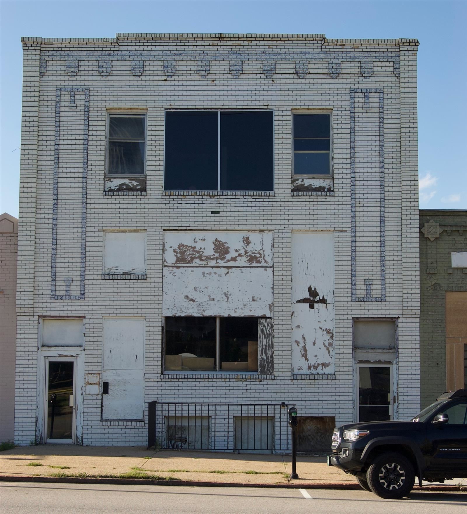 Modern image of a damaged building with boarded windows and a worn facade